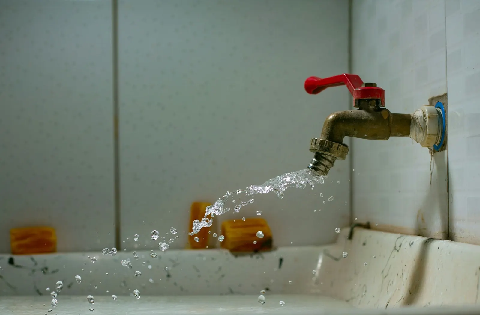 Water spraying from a brass tap over a utility sink