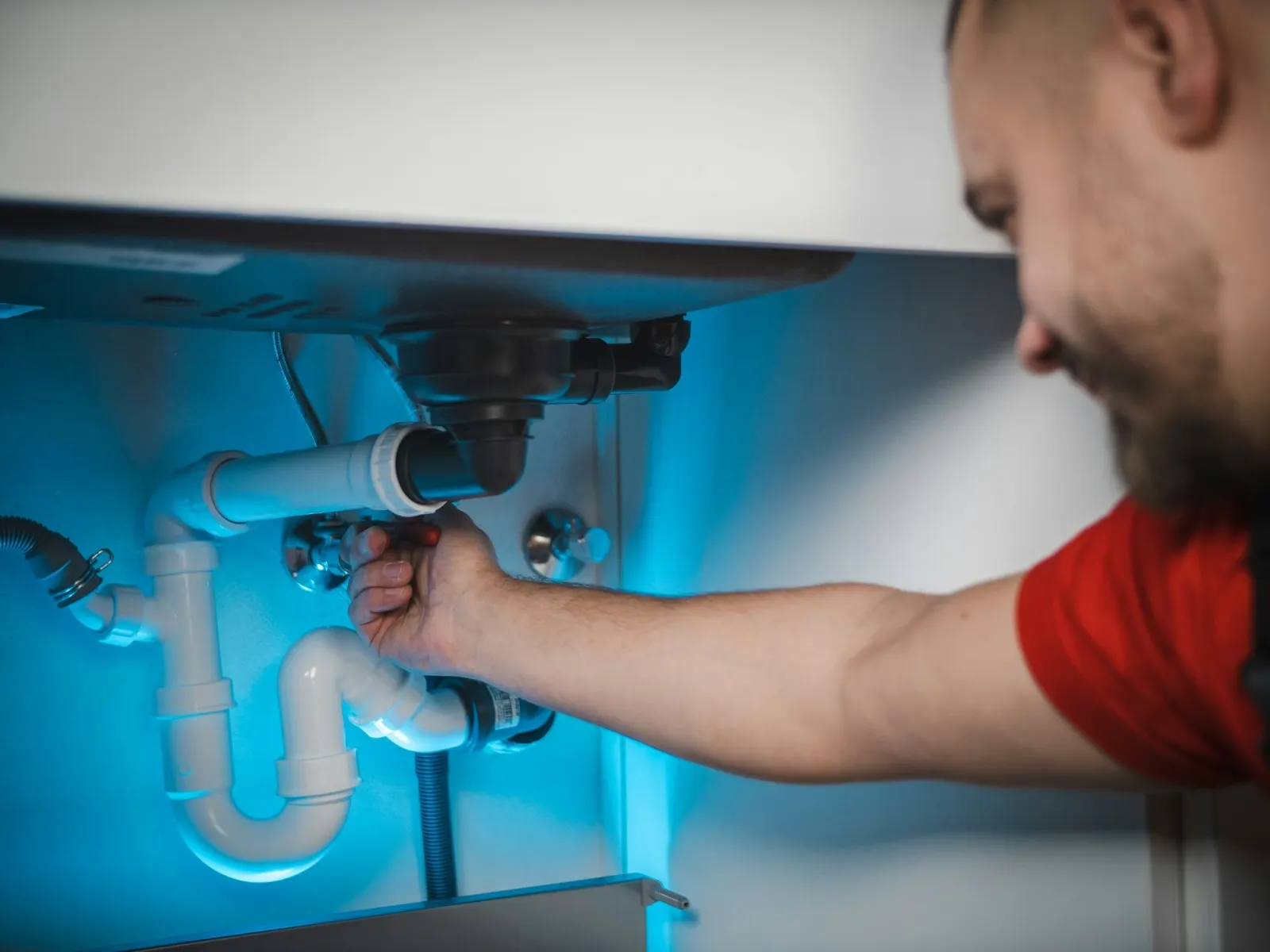 Smiling plumber adjusting the drain trap under a bathroom sink
